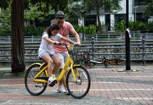 Image of a father helping a child to learn to ride a bike