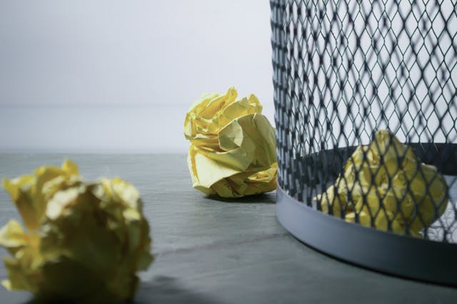 Image of screwed up papers in and outside a waste paper basket